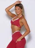 left side profile view of a model wearing the Contrast Voltage Sports Bra in maroon color