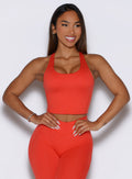 Frontal view of the model with both hands on her waist, wearing our Core Comfort Tank in Inferno color, and paired with matching leggings.
