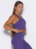 A right side profile shot of the model adjusting the Core Comfort Tank in Iris color.