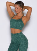 front profile view of a model wearing the Cross Fit Bra in Emerald Green Cheetah color