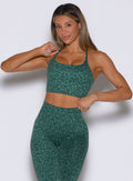 front profile view of a model wearing the Cross Fit Bra in Emerald Green Cheetah color paired with the matching leggings