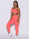 front left side profile view of a model wearing the Curvemax leggings in neon apricot pink color 
