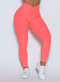 close up front profile view of a model wearing the Curvemax leggings in neon apricot pink color 