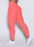 close up back left side profile view of a model wearing the Curvemax leggings in neon apricot pink color 