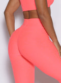zoomed in back right side profile view of a model wearing the Curvemax leggings in neon apricot pink color 