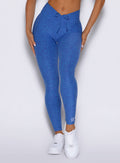 close up front view of a model showcasing the V cut waistband wearing the Curvemax leggings in neon blue rave color 