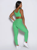 side profile view of a model showcasing the V cut waistband wearing the Curvemax leggings in neon miami beach color 