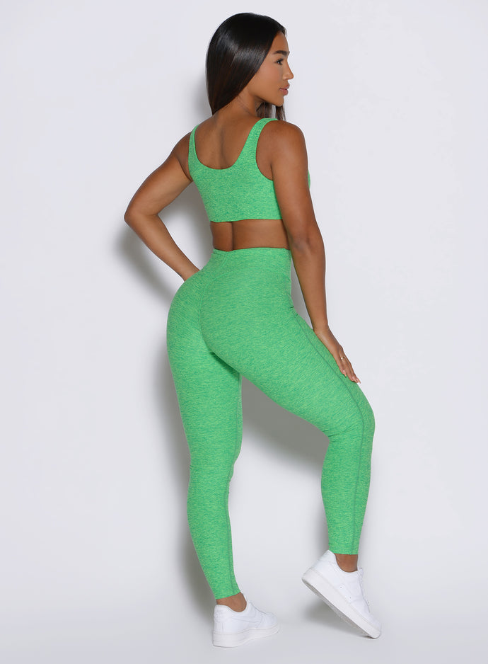 side profile view of a model showcasing the V cut waistband wearing the Curvemax leggings in neon miami beach color 