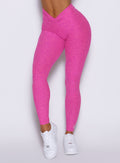 close up front view of a model showcasing the V cut waistband with the hide-able ties wearing the Curvemax leggings in neon pink sorbet color