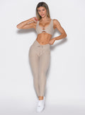 front profile view of a model facing to the left side wearing the Curvemax leggings in Taupe color