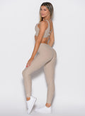 left side profile view of a model looking over her shoulder wearing the Curvemax leggings in Taupe color
