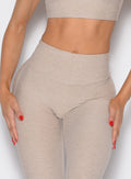 close up front profile view of a model with both hands on her thighs wearing the Curvemax leggings in Taupe color