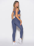 right side profile view of a model looking over her shoulder wearing the Curvemax leggings in wisteria blue color
