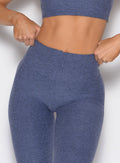 close up front profile view of a model with both hands on the waistband wearing the Curvemax leggings in wisteria blue color