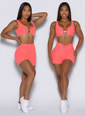 front view of a model showcasing straight and V cut waistband on the Curvemax shorts in neon apricot pink color