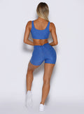 back side profile view of a model wearing the Curvemax shorts in neon blue rave color