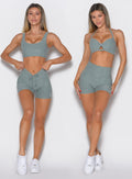 front profile view of a model wearing the Curvemax Shorts in sea moss color showcasing the adjusted and non-adjusted version of the waistband side by side 