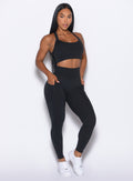 front right side profile view of our model with both hands in the pockets of the leggings wearing the Curves Leggings in Black color