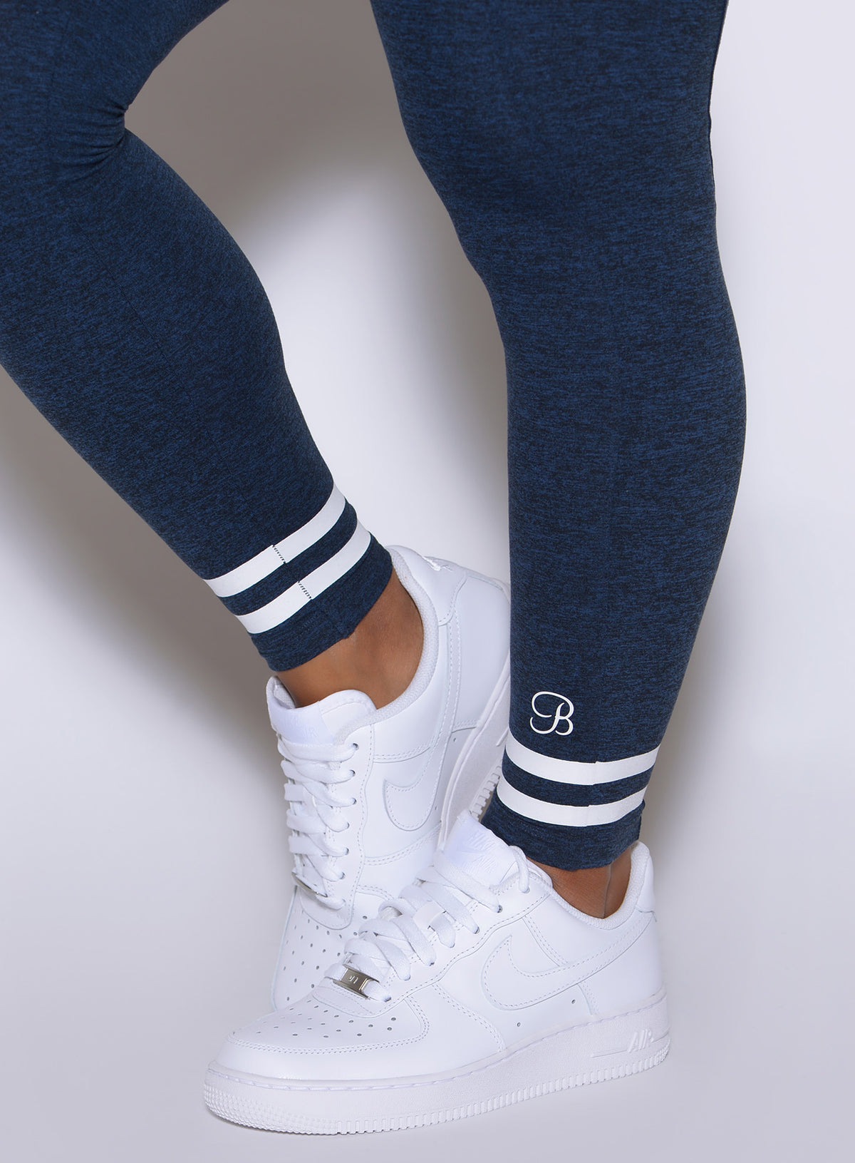 Detailed lower leg close-up featuring classic two-stripe ankle cuffs and crisp white sneakers.