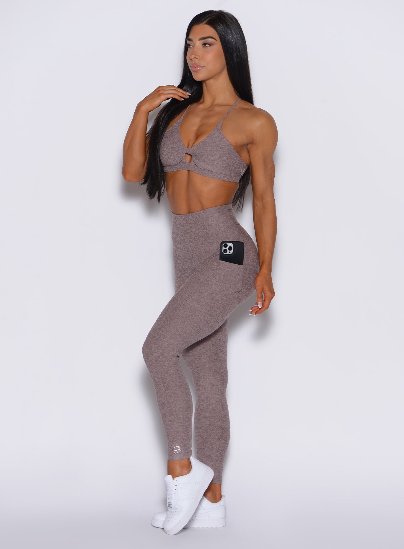 left side profile view of a model angled slightly to her left wearing our curves leggings in london fog color along with the matching sports bra 