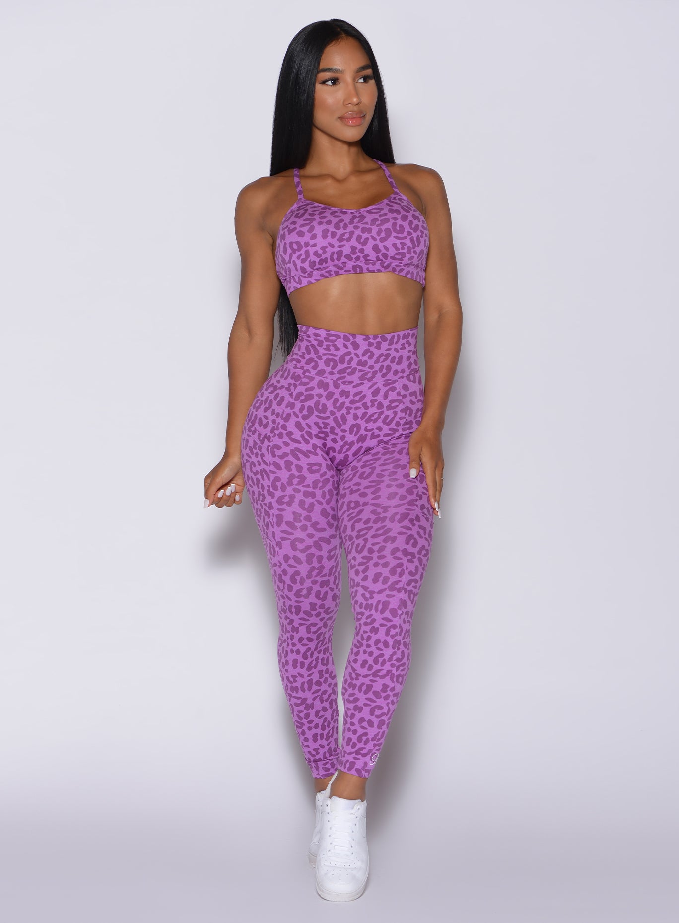 Front profile view of a model in our curves leggings in purple cheetah color and a matching sports bra
