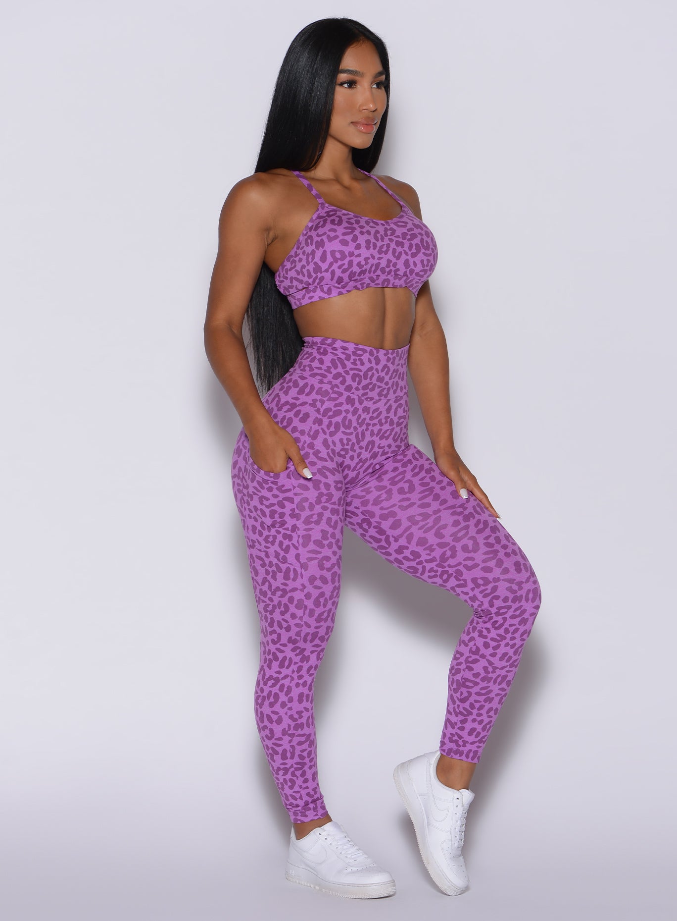 Right side profile view of a model in our curves leggings in purple cheetah color and a matching sports bra