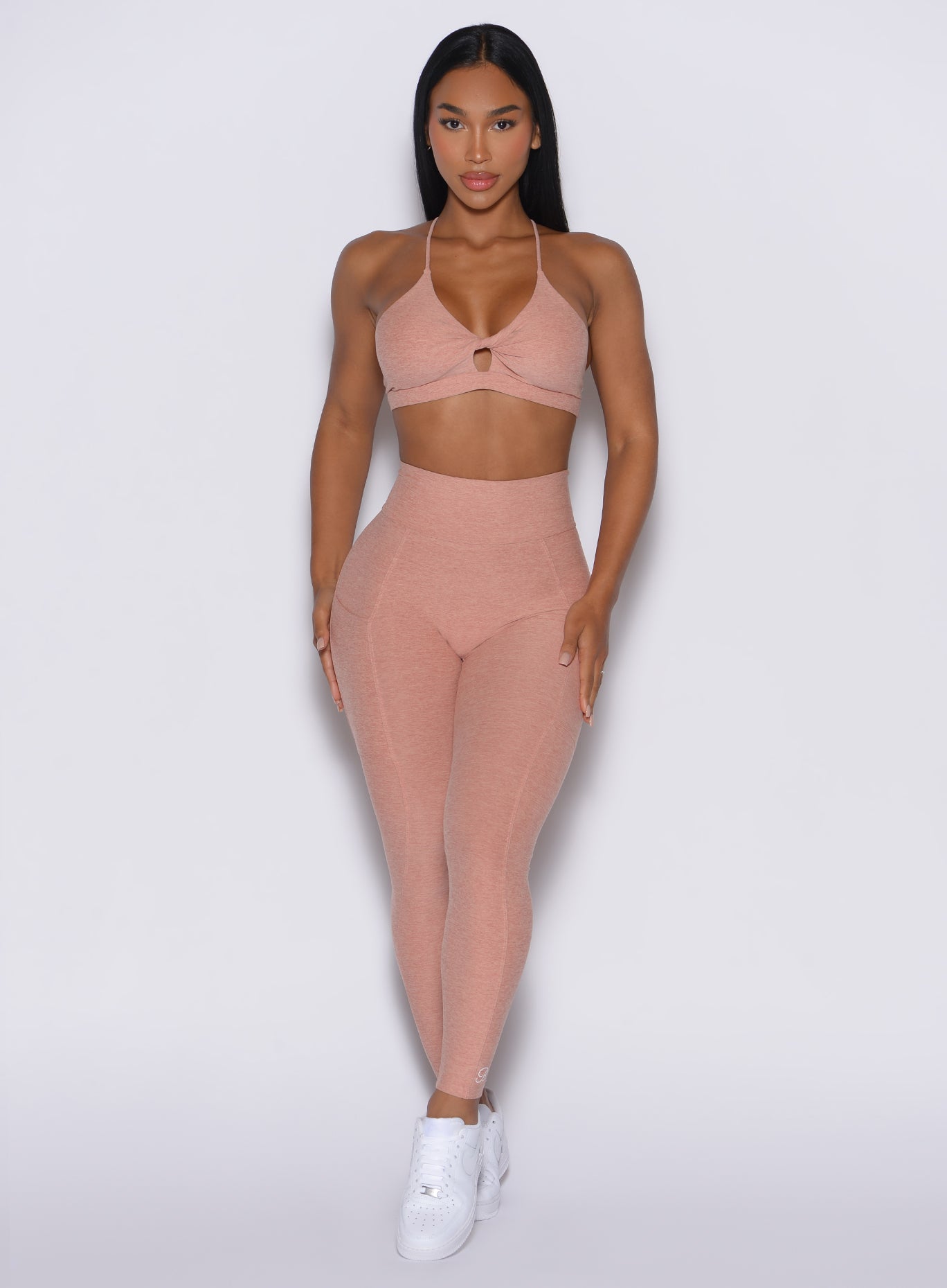 A front-profile view of a model wearing our Curves leggings in Nude Sand color, paired with the matching sports bra.