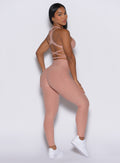 back profile view of a model facing to her right wearing our Curves leggings in Nude Sand color, paired with the matching sports bra.