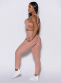 left side profile view of a model wearing our Curves leggings in Nude Sand color, paired with the matching twist sports bra.