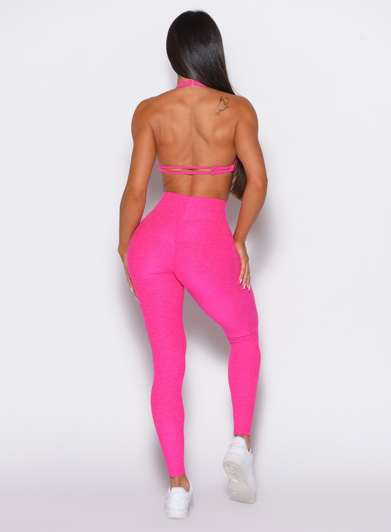 back  profile view of a model wearing our curves leggings in Neon Pink Berry color along with the matching bra