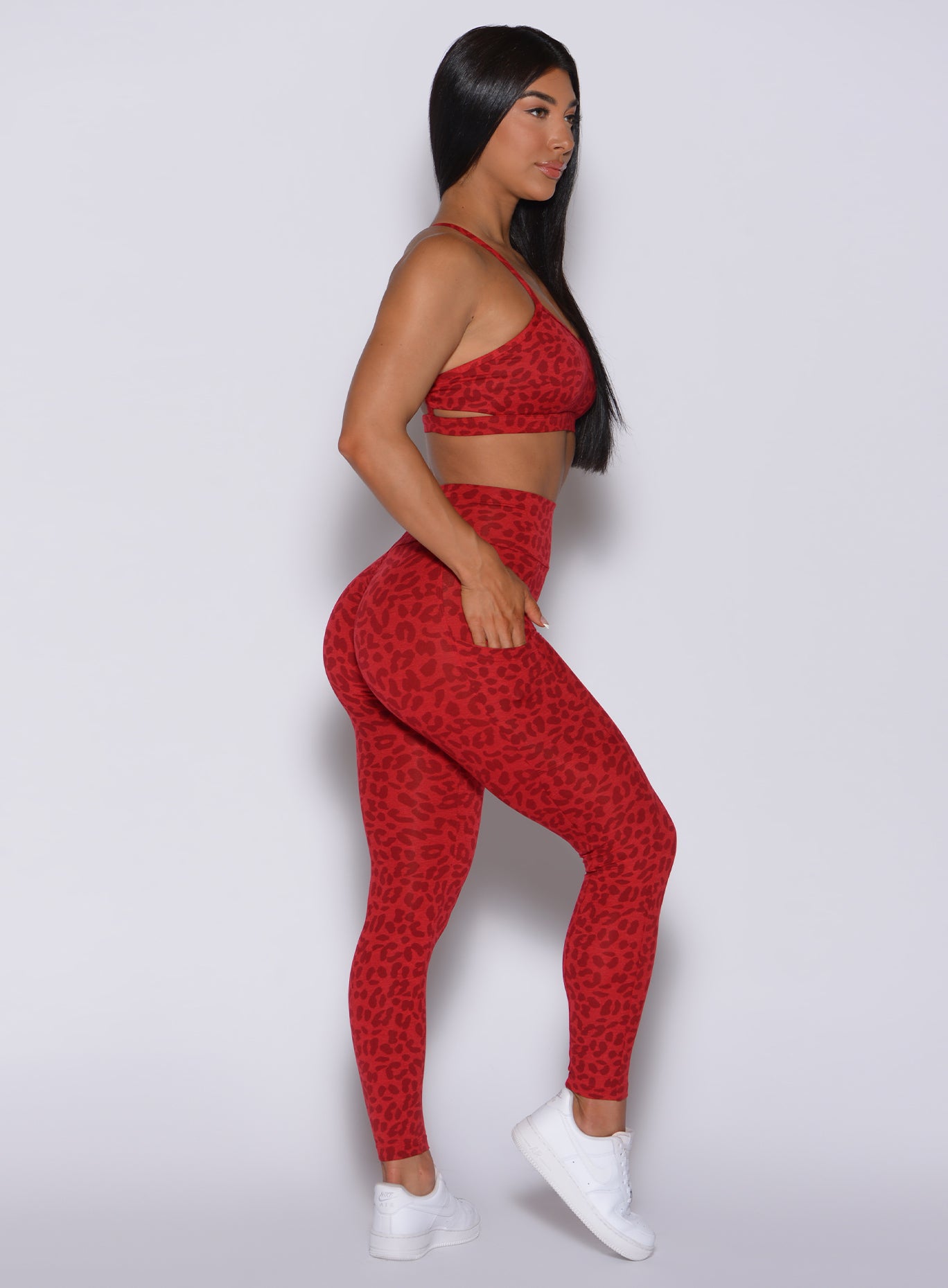 Right side profile view of a model in our curves leggings in red cheetah color and a matching sports bra