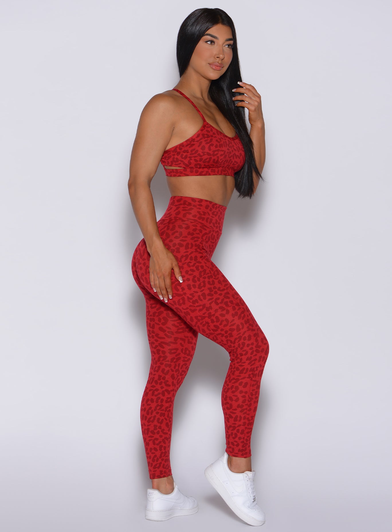Right side profile view of a model wearing our curves leggings in red cheetah color and a matching sports bra