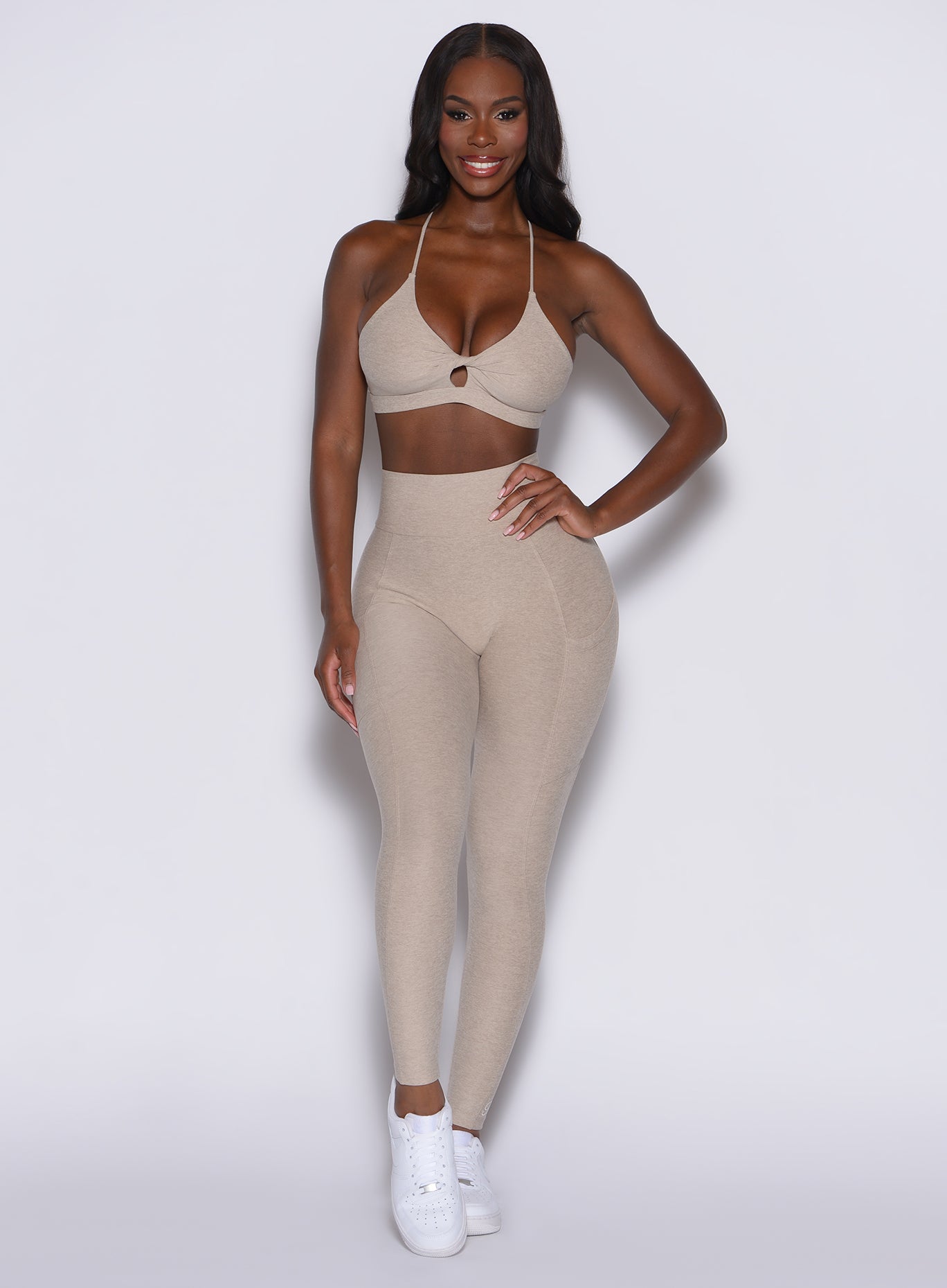 front profile view of a model wearing our Curves leggings in taupe color, paired with the matching sports bra.