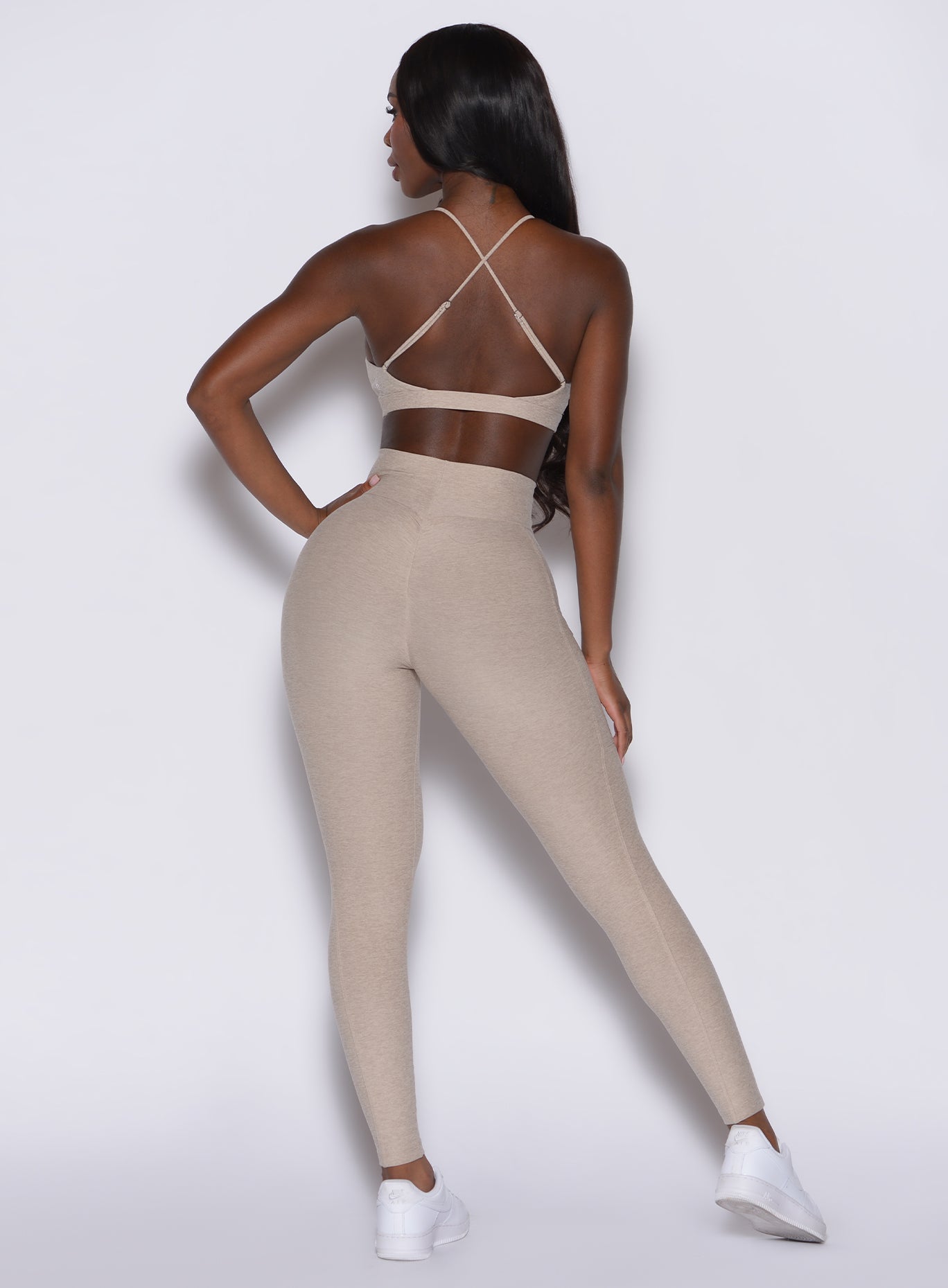 back profile view of a model wearing our Curves leggings in taupe color, paired with the matching sports bra.