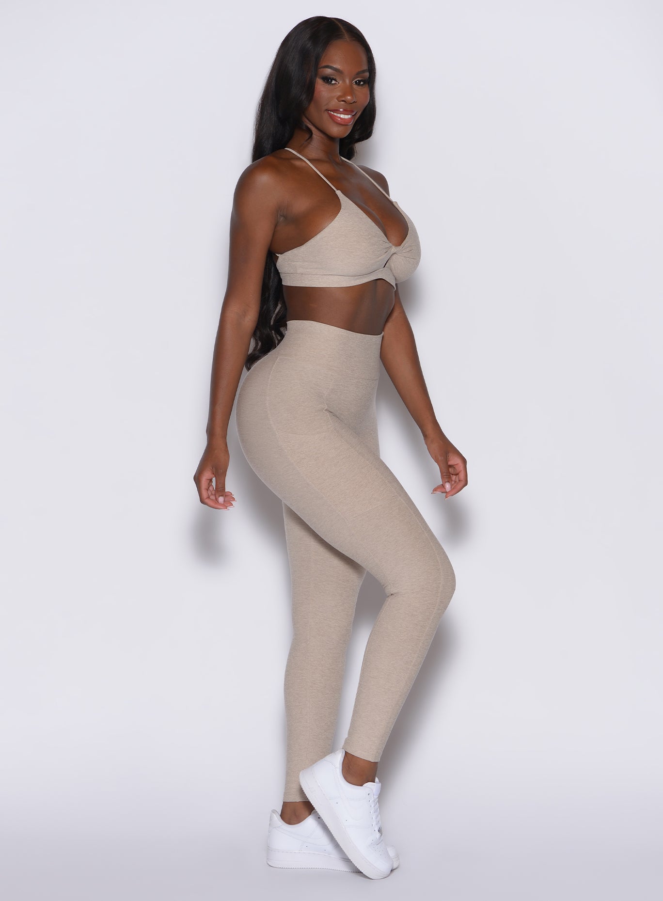 right side profile view of a model wearing our Curves leggings in taupe color, paired with the matching sports bra.