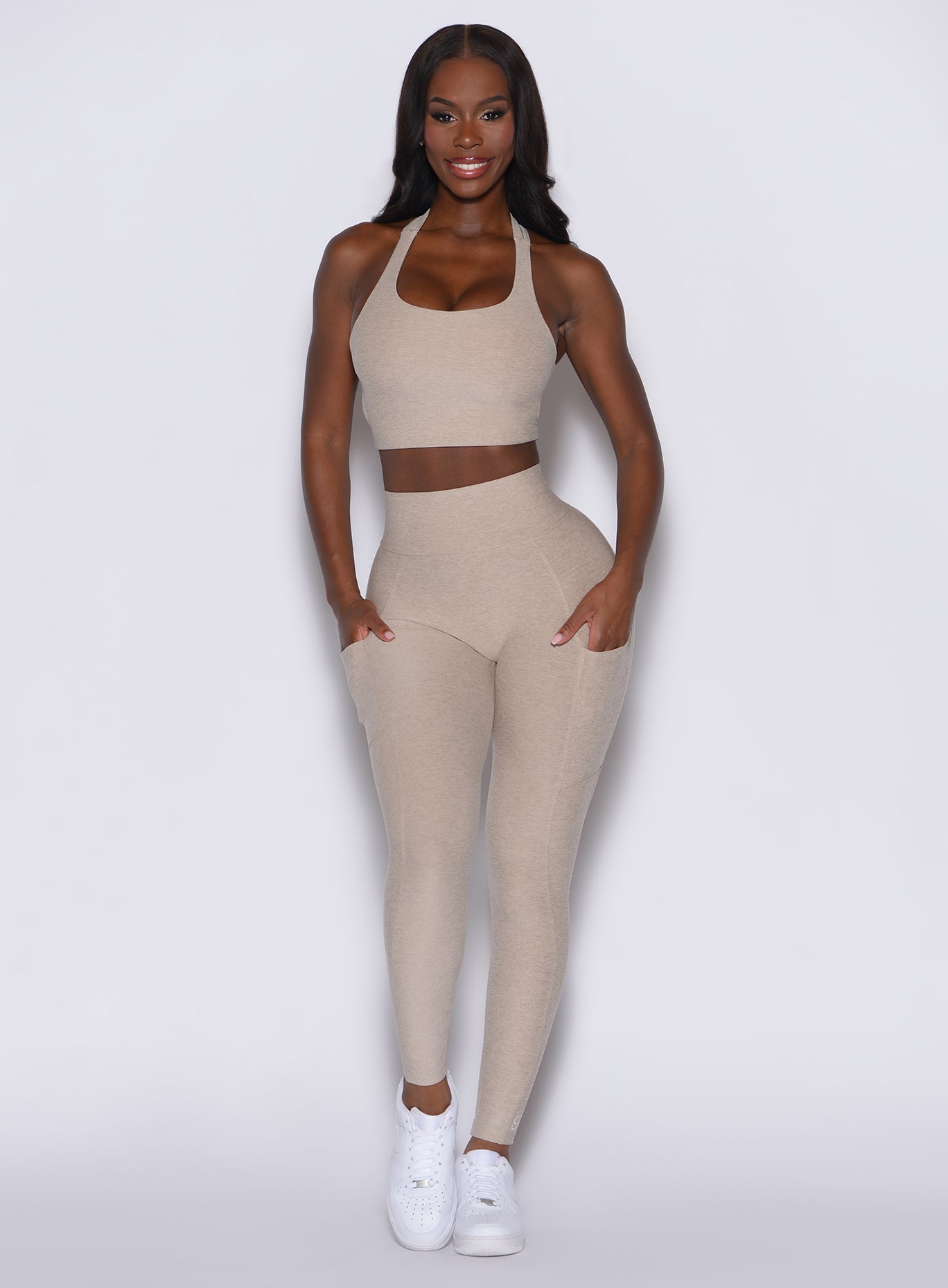 front profile view of a model facing forward wearing our Curves leggings in taupe color, paired with the matching sports bra.