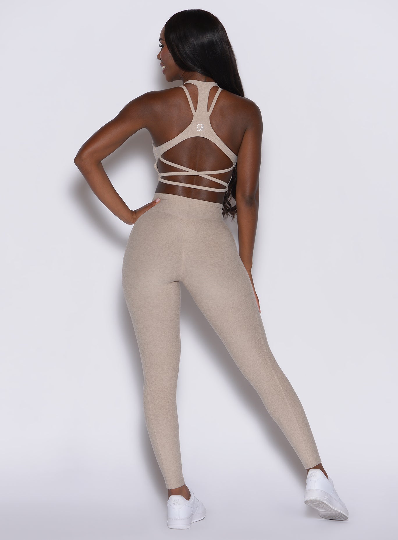 Back profile view of a model wearing our Curves leggings in taupe color along with the matching sports bra.