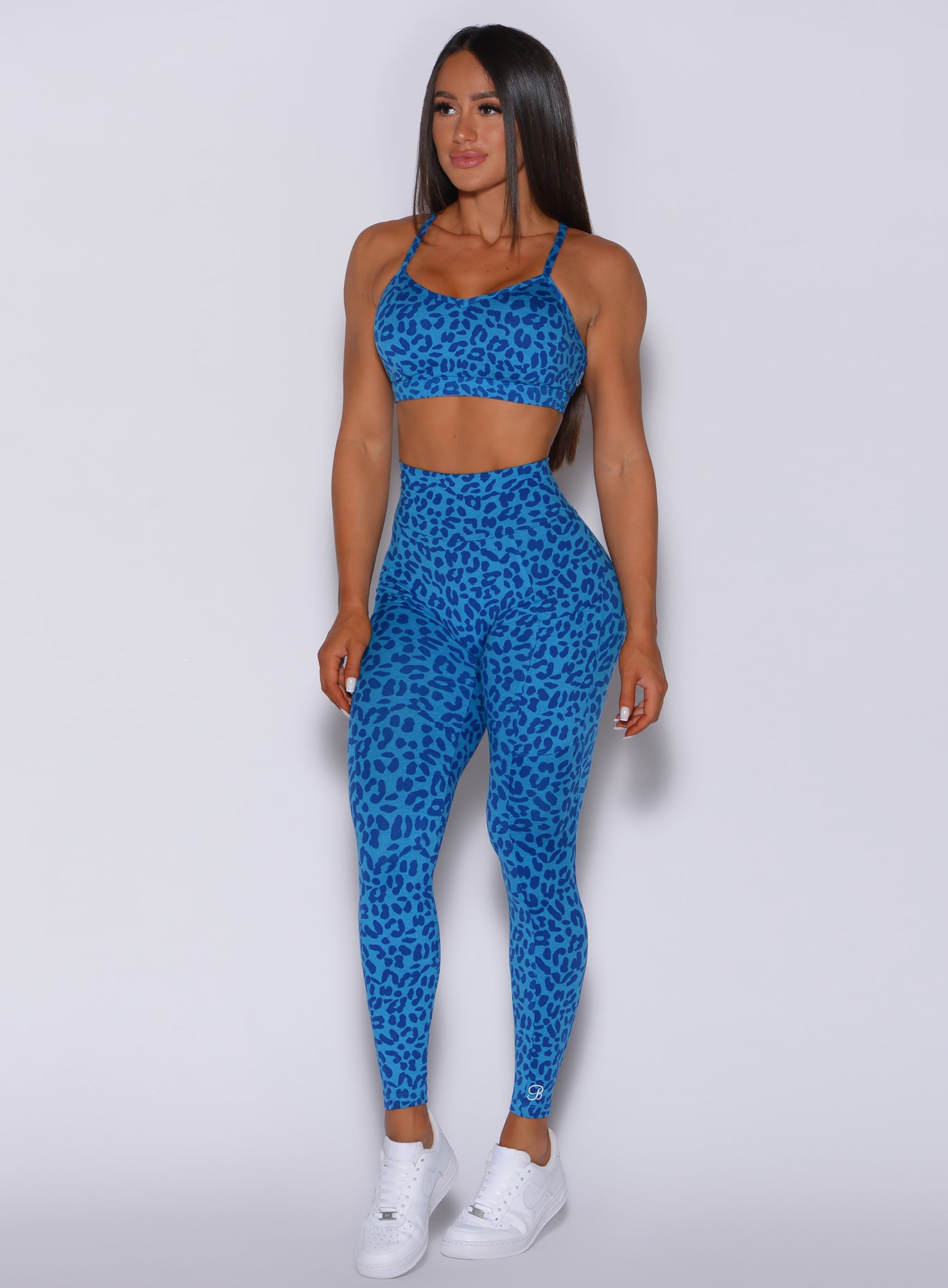 Front  profile view of a model facing to her right wearing our curves leggings in blue cheetah color and a matching bra