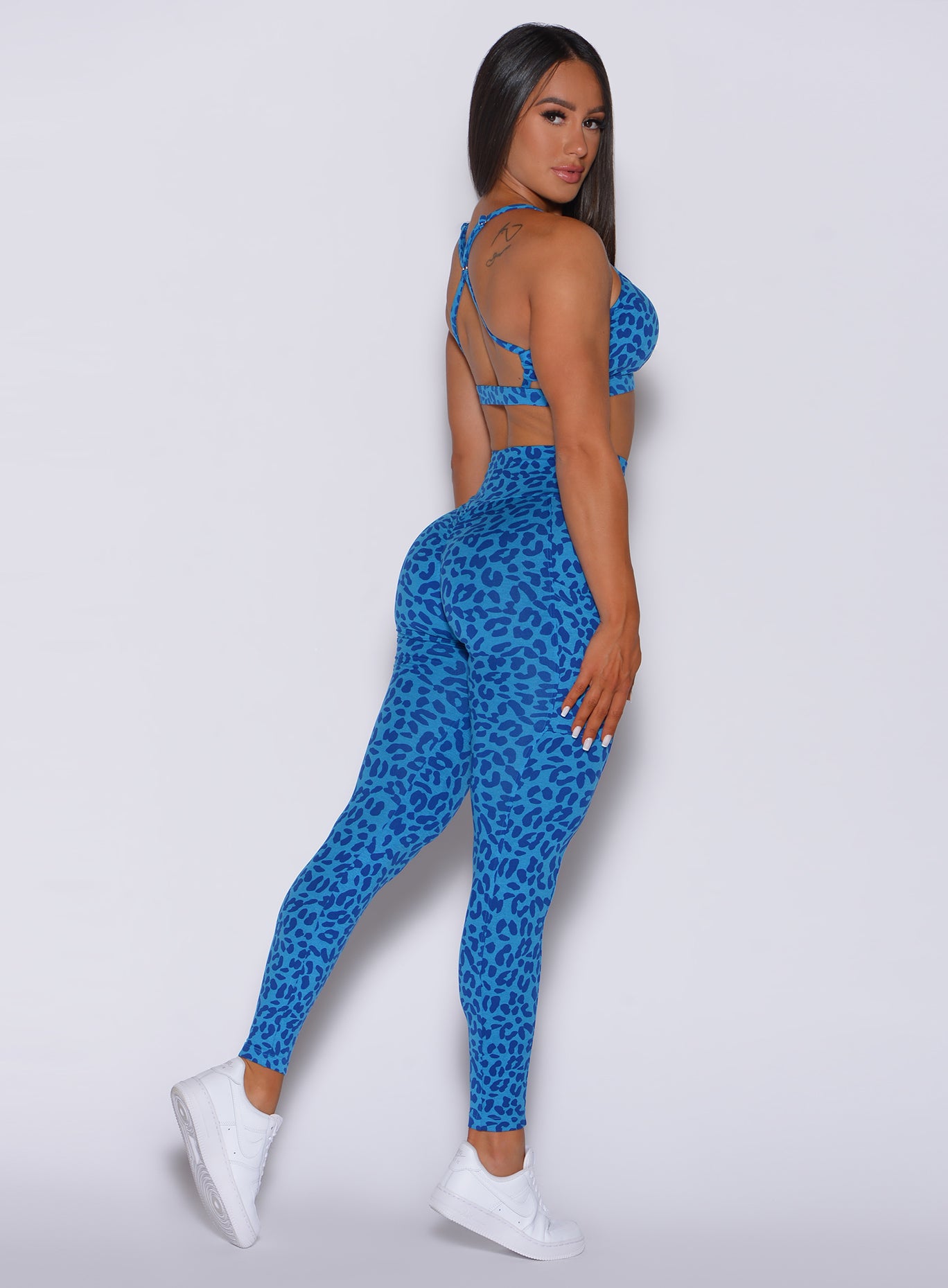 Right side profile view of a model in our curves leggings in blue cheetah color and a matching bra