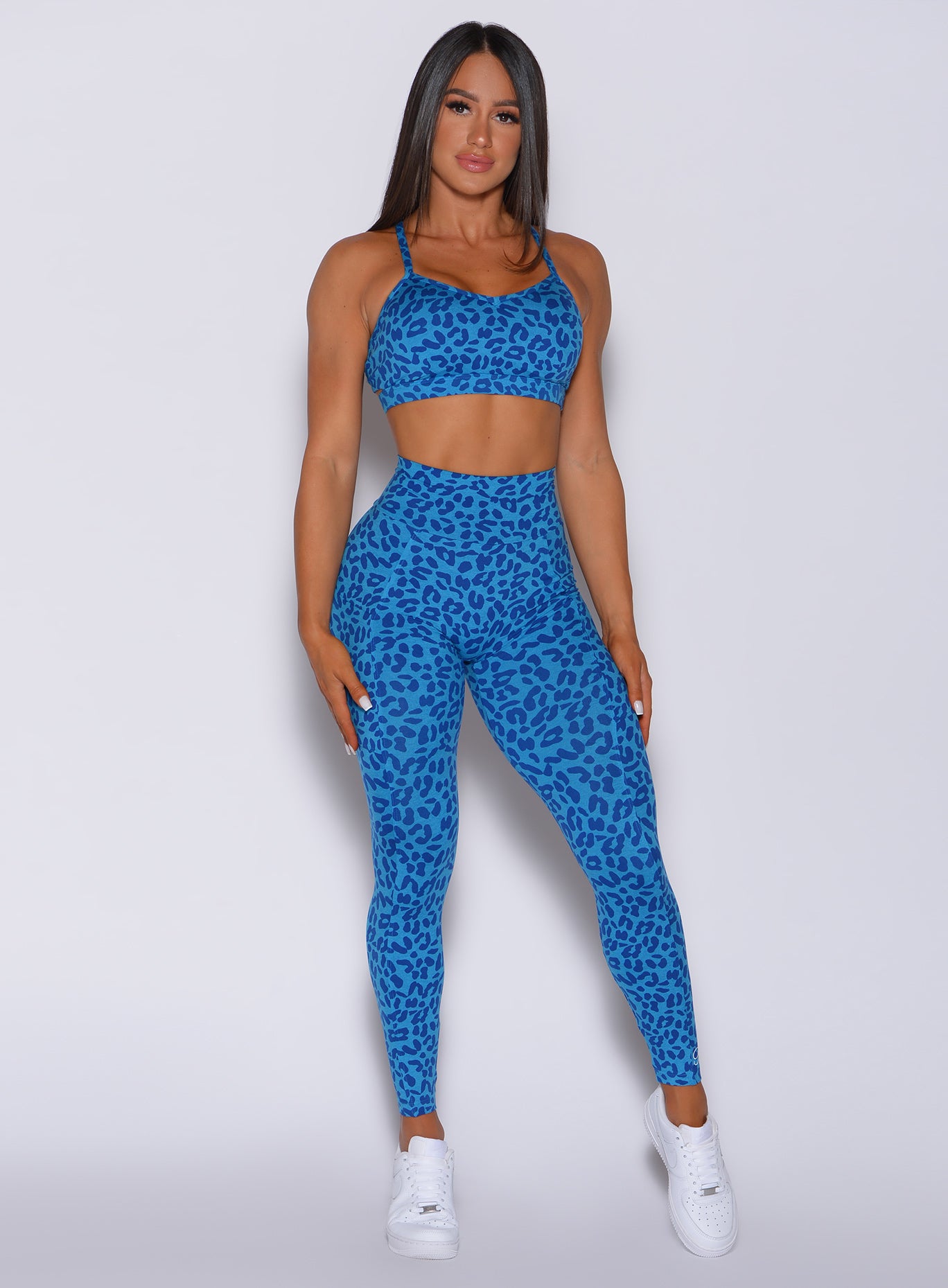 Picture of a model facing forward wearing our curves leggings in blue cheetah color and a matching bra 