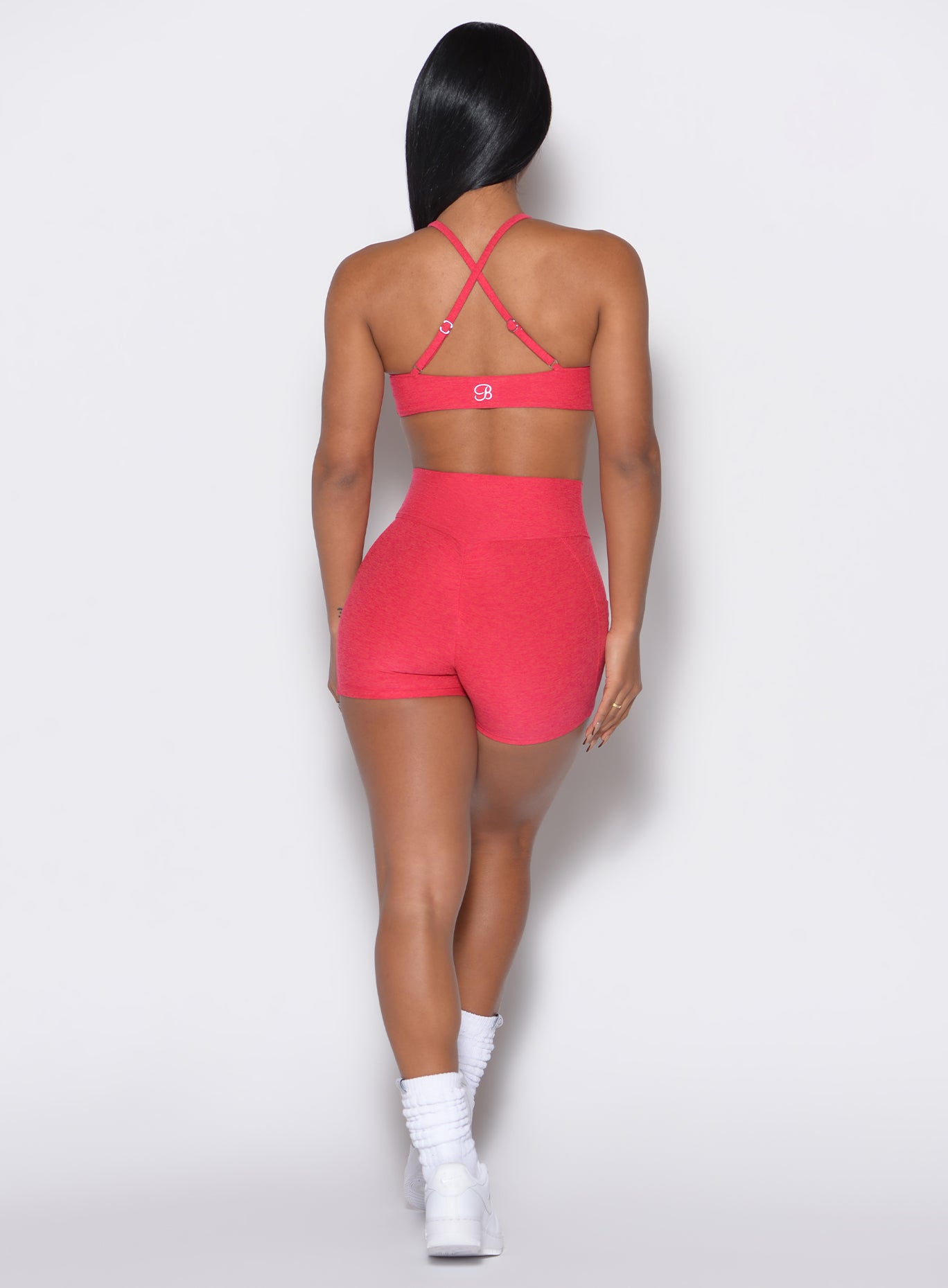 back  profile view of a model wearing our scrunch shorts in Raspberry Punch color along with a matching bra
