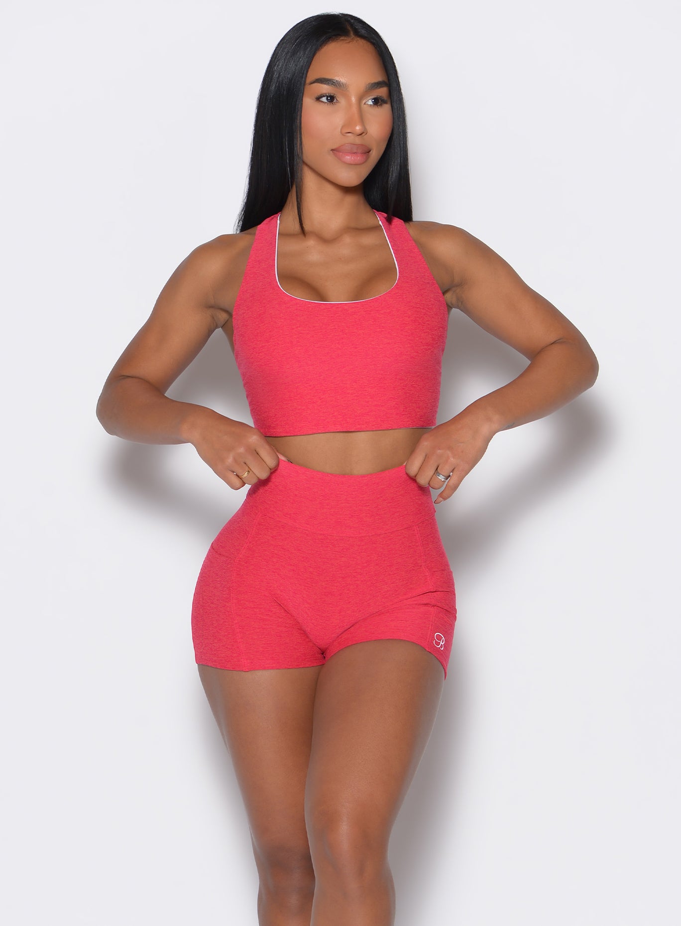 front profile view of a model wearing a reversible tank bra in raspberry punch color along with a matching shorts 