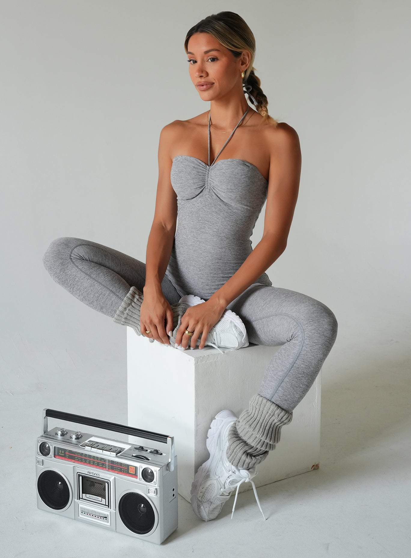 model sitting on a block wearing the flawless form bodysuit in dark and stormy color