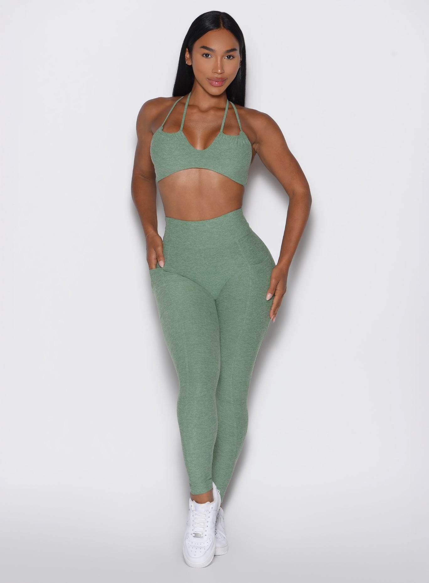 front profile view of a model wearing the Define Leggings in basil color paired with the matching bra