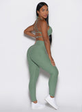right side profile view of a model wearing the Define Leggings in basil color