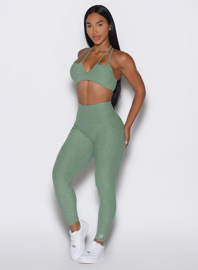 front profile view of a model wearing the Define Leggings in basil color paired with the matching bra