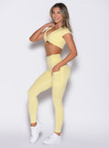 front left side profile view of a model with one hand inside the pocket of the leggings wearing the Define Leggings in Soft Yellow color