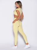 left side profile view of a model wearing the Define Leggings in Soft Yellow color
