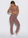 front profile view of a model with one hand on the waistband wearing the Define Leggings in walnut color