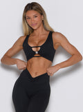 Woman wearing a black sports bra and leggings on a white background